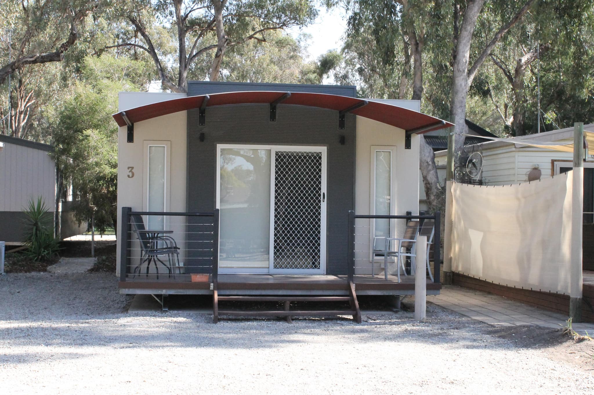 Fleetwood Rainbow Cabin number 3 with curved red awning and timber deck at Torrumbarry Weir Holiday Park, Patho VIC