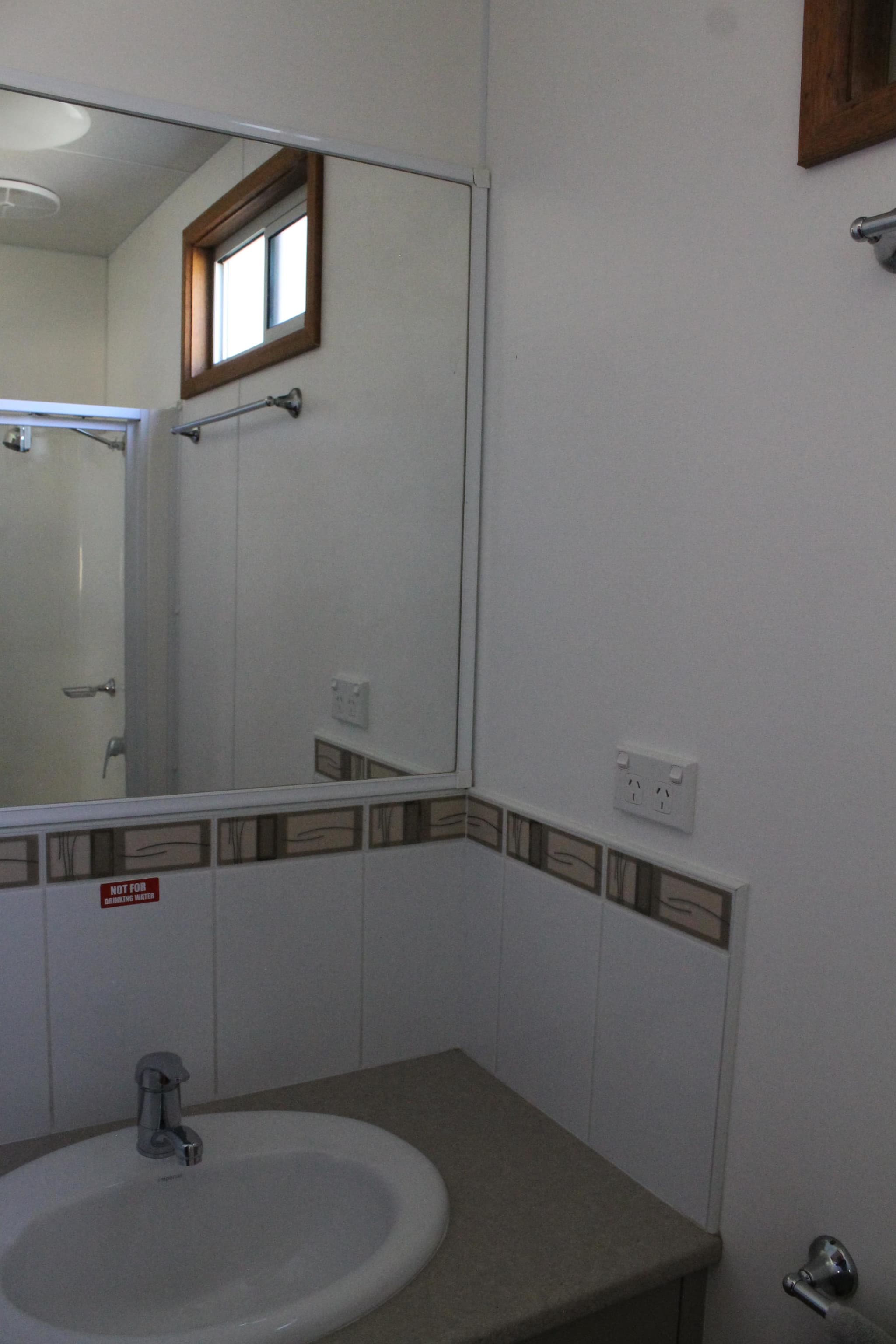 Ensuite bathroom in the Fleetwood Rainbow Cabin at Torrumbarry Weir Holiday Park, with vanity sink, mirror and tiled shower recess