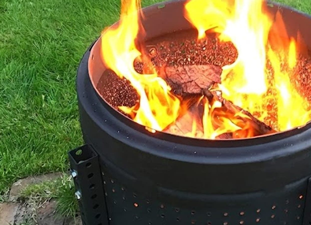 Black metal drum fire pit for hire burning brightly on the lawn at Torrumbarry Weir Holiday Park, Patho VIC