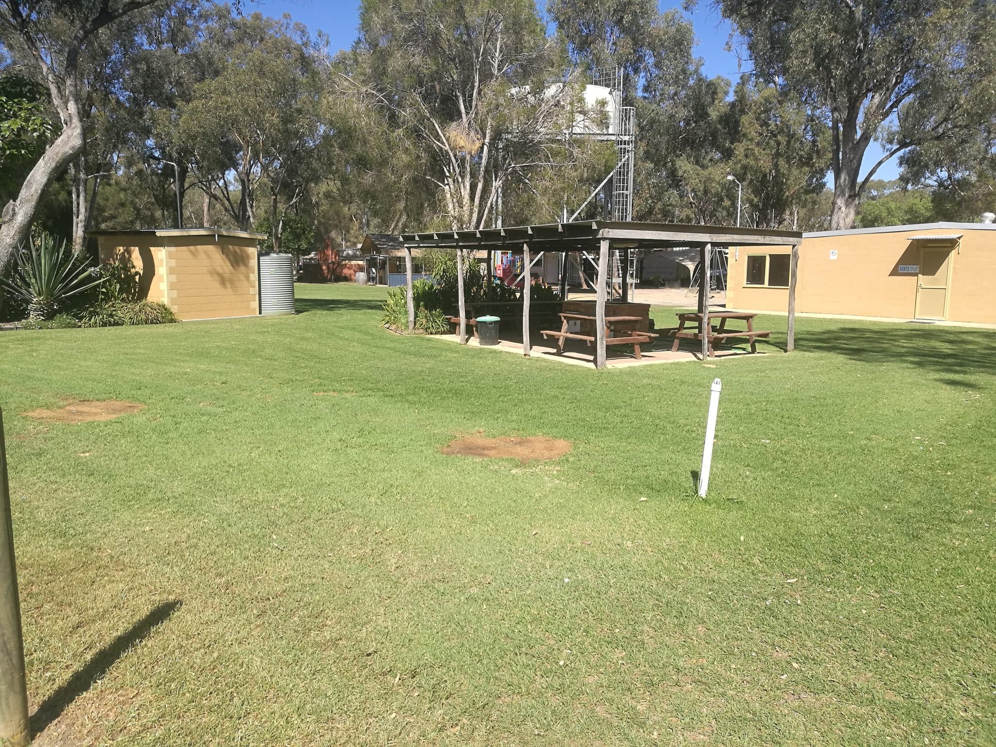 Open-sided timber camp kitchen shelter with picnic tables on a grassy lawn at Torrumbarry Weir Holiday Park, Patho VIC