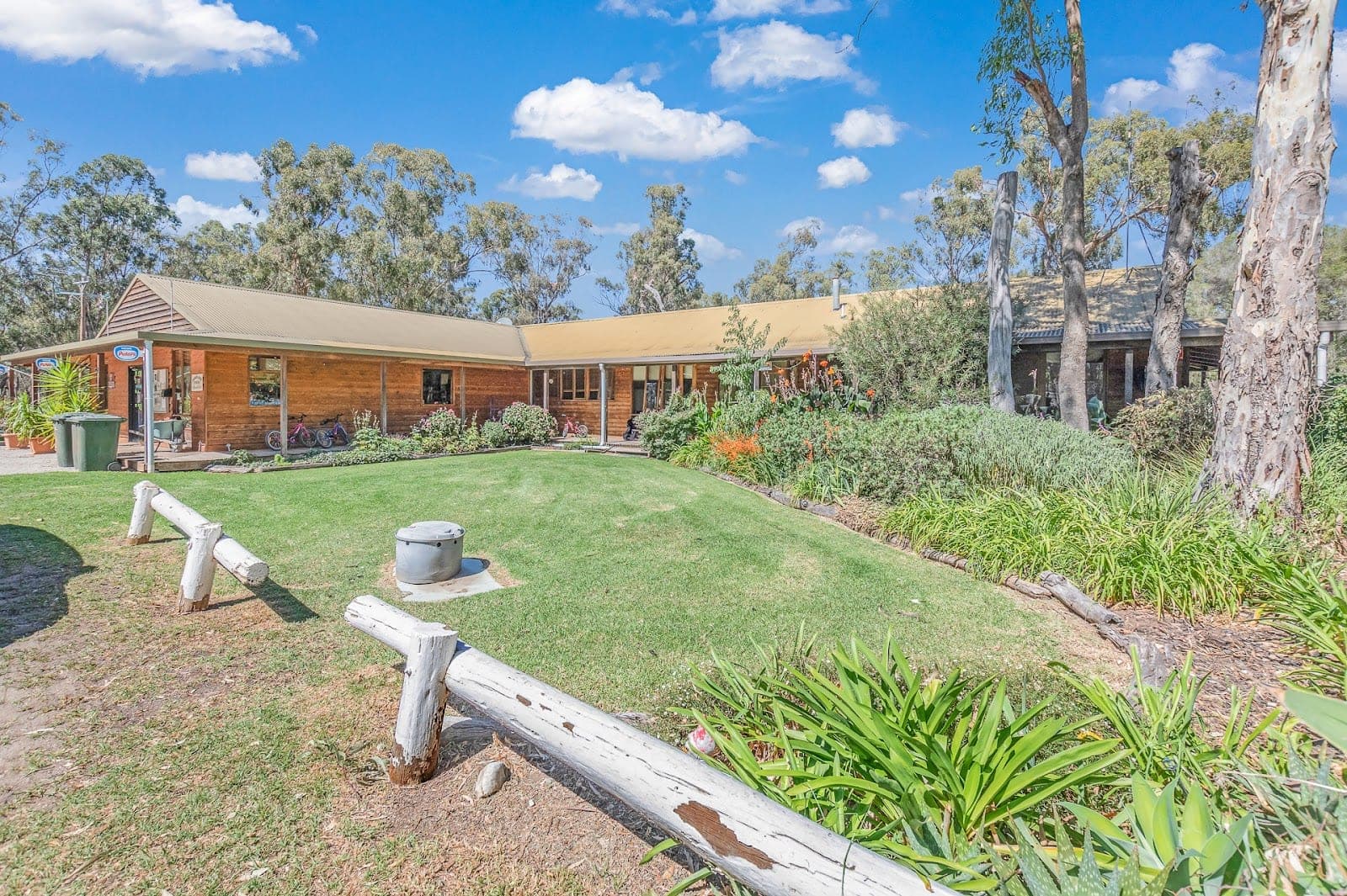 Timber cabin office with wraparound verandah, lawn and native gardens at Torrumbarry Weir Holiday Park, Patho VIC